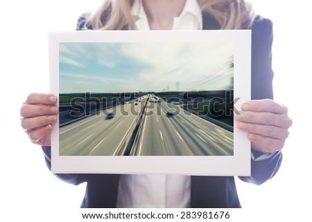 Young businesswoman behind white board with picture of highway on white background