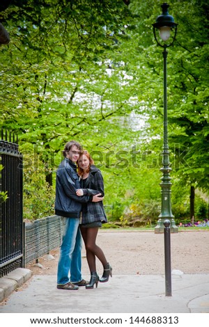 Lovers look at a camera and hugging in Paris in the park near Eiffel Tower