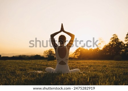 Foto Bild Frau meditiert und übt Yoga, Padmasana. Meditation auf sonnigen Herbsttag im Park. Workout im Freien.