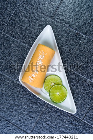 top view fruit yellow cake roll with lemon cut at outdoor sunshade