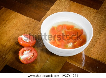 tomato asia style soup food in bowl with fresh cut tomato on parquet background