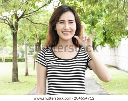 Happy asia young woman with make symbol love sign by hand in a natural at outdoor