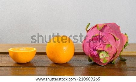 ripe dragon fruit and orange fruit on wooden  table on concrete background