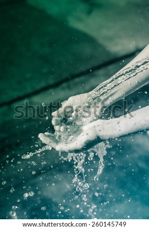 Woman\'s wash hands and water splash with retro filter at outdoor