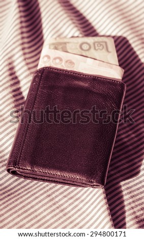 leather wallet purse and thai money on fabric at outdoor