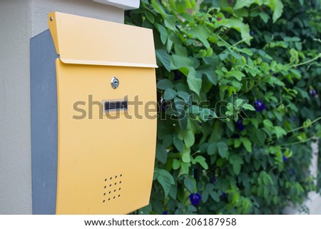 yellow metal mailbox with green leaves background