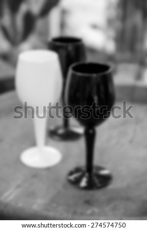 blurry defocused image of black and white wine glass on wooden desk for background