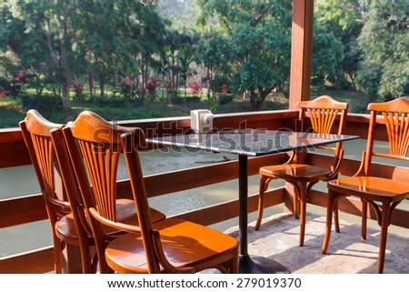 wooden table and chair on the terrace beside the river