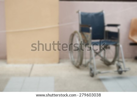 blurry defocused image of old wheelchair beside the beige wall of the building for background