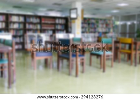 blurry defocused image of book shelf, wooden desk and chair for reading book in the university ibrary