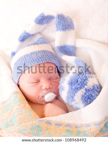 newborn baby (at the age of 7 days) sleeps in a knitted striped hat
