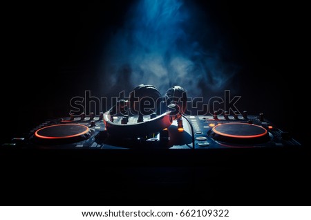 DJ Spinning, Mixing, and Scratching in a Night Club, Hands of dj various track controls on dj's deck, strobe lights and fog, selective focus, close up Сток-фото © 