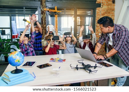 Korean male scientist with young pupils with laptop and VR headsets during a computer science class. Excited schoolchildren of smart modern school use virtual reality for studying new tecnologies. Foto stock © 