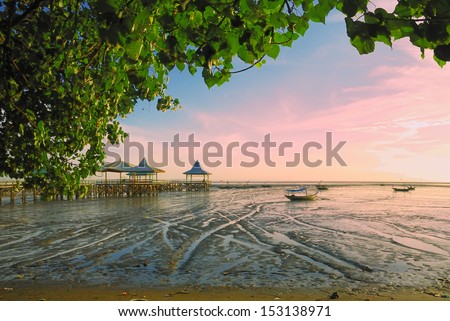 Receding shore with green leaves frame. taken at Kenjeran beach, Surabaya, east Java, Indonesia