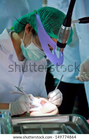 Photo of female patient with dentist over her checking up teeth and drilling them