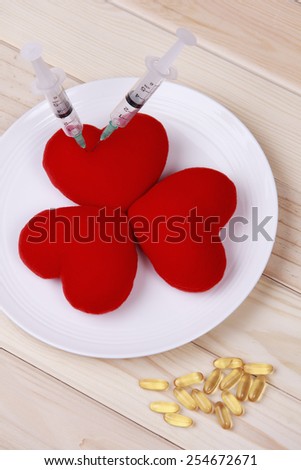 concept red heart on plate with syringe and stimulant on wood background.Health care yourself should be done.