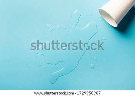 Cup with spilled water on a blue background. Abstract light. Ice concept for drinks. Banner. Flat lay, top view Foto stock © 
