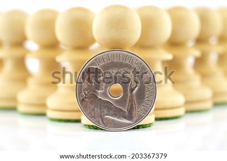 Several chess pieces with an old Spanish coin representing the Republican hope of the Spanish people isolated on white background.