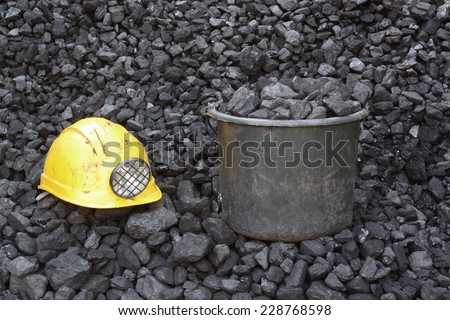 Bucket of coal and helmet coal miner