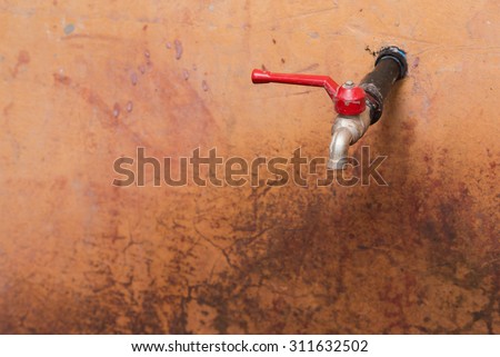 Water faucets on a old and vintage red concrete wall, with selective focus on the faucets.