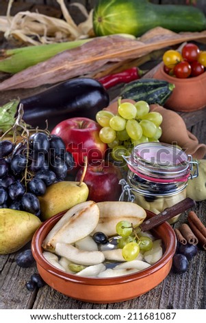 Fruit compote of pears with grapes surrounded by fresh fruit and vegetables
