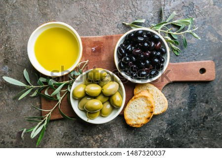 A set of Green and black olives and olive oil on a dark stone background, top view