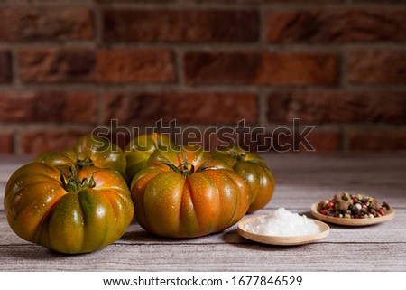 Group of raf tomatoes with salt and peppercorns on wooden table and brick background. Copy space Zdjęcia stock © 
