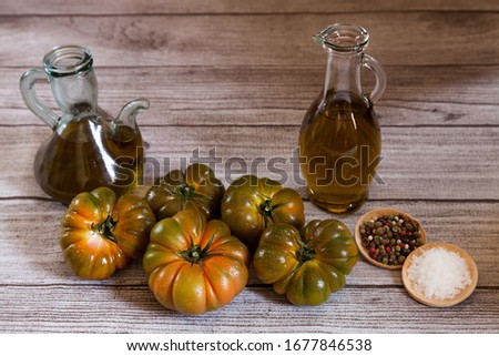 Two olive oil bottles, raf tomatoes, salt and peppercorns in wooden plate on wooden background. copy space Zdjęcia stock © 