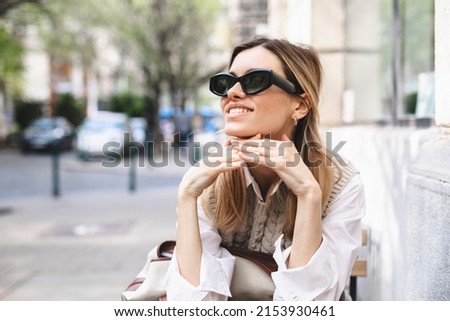 Young woman sitting on a street outside in coffee shop waiting order, holding her head and look at side.  Foto stock © 