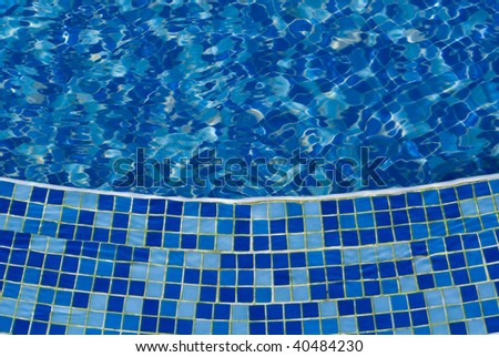 The photo of pool with water covered with blue mosaic