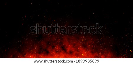 Fire embers particles over black background. Fire sparks background. Abstract dark glitter fire particles lights. bonfire in motion blur.