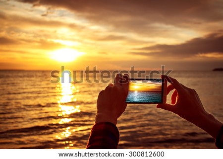 woman hands holding mobile phone at sunset