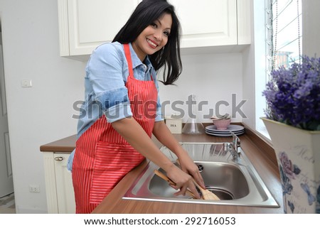Woman doing the washing up in kitchen
