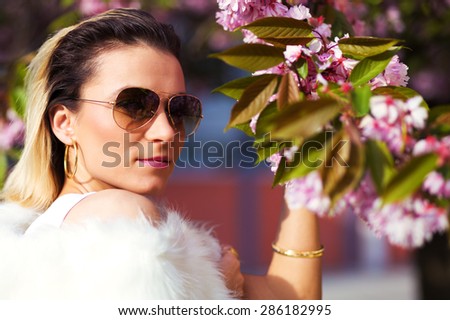 Beautiful Girl with flowers, Spring Magic. Sakura pink flowers. With glamour white fur, and sunglasses