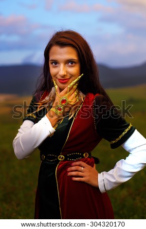 Smiling  Young woman with ornamental dress and hand jewel. Natural background.