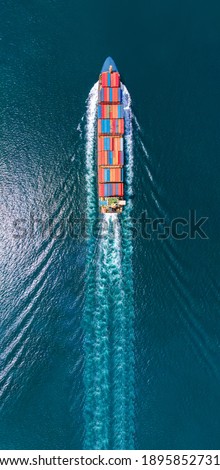 Aerial portrait view of smart cargo ship with contrail in the ocean sea ship carrying container from custom container depot go to ocean concept freight shipping by ship service.