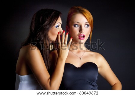 Two happy young girlfriends telling secrets.