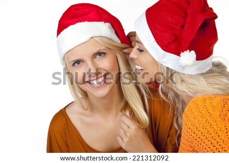 Two girls in Santa hat isolated on white, whispering