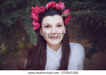 Charming girl in white blouse with wreath of tulips on her head. Outdoor