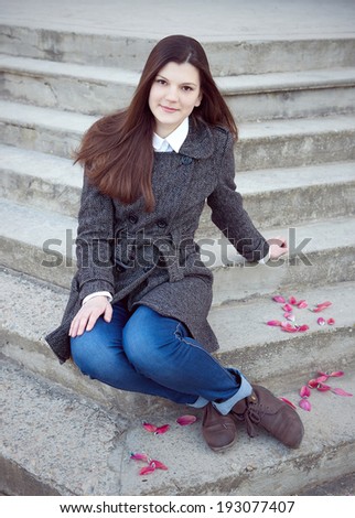 Cute teenage girl sitting on the steps of the ladder. Outdoor