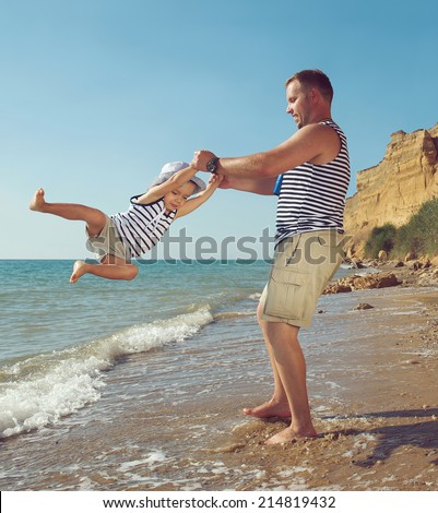 Young man playing with his son at the sea coast. Summer vacation