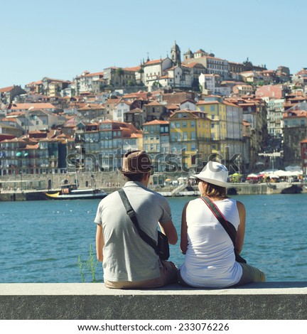 PORTO, PORTUGAL - AUGUST 11, 2013: Tourists sitting on the bank of the Douro River in Porto