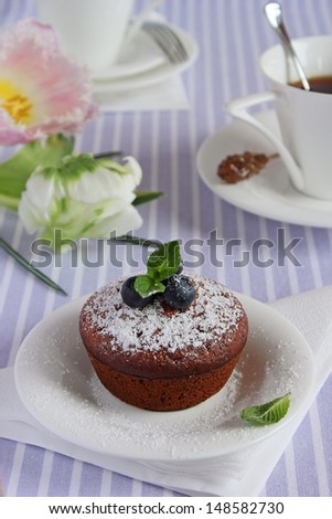 Blueberry muffin and flowers on the lilac background