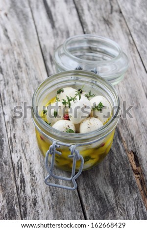In olive oil marinated mozzarella with thyme and  pepper on a wooden background