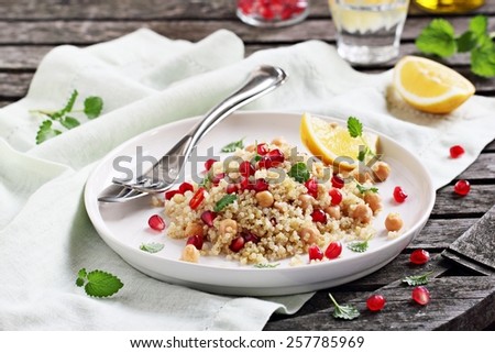 Quinoa salad with chickpeas,pomegranate and mint on a rustic wooden table.Selective focus.