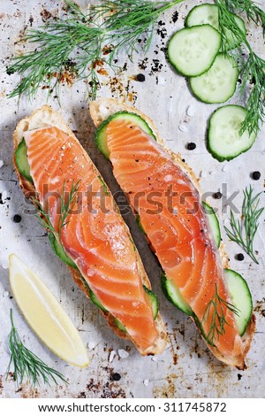 Sandwich with smoked salmon and cucumber on grilled baguette . Selective focus.