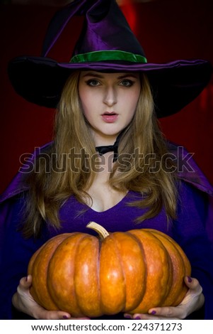 The witch in purple cloak and a hat with an orange pumpkin on halloween