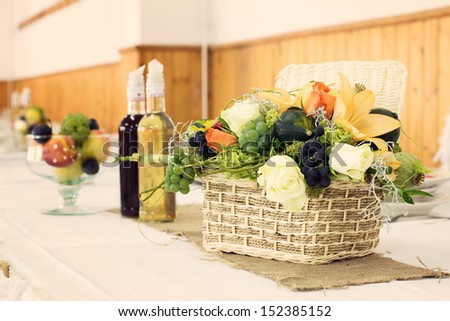 Decorative Centerpiece Wicker Basket with fruits and flowers, brandy and fruit dish in table