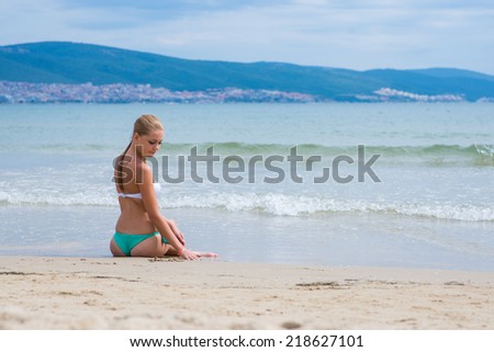 young female enjoying sun and write in sand on a beach