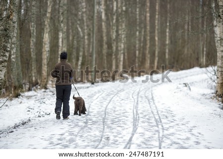 A woman walking the dog in the park.